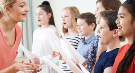 Teacher standing in front of six students as they learn a song in Chorus 